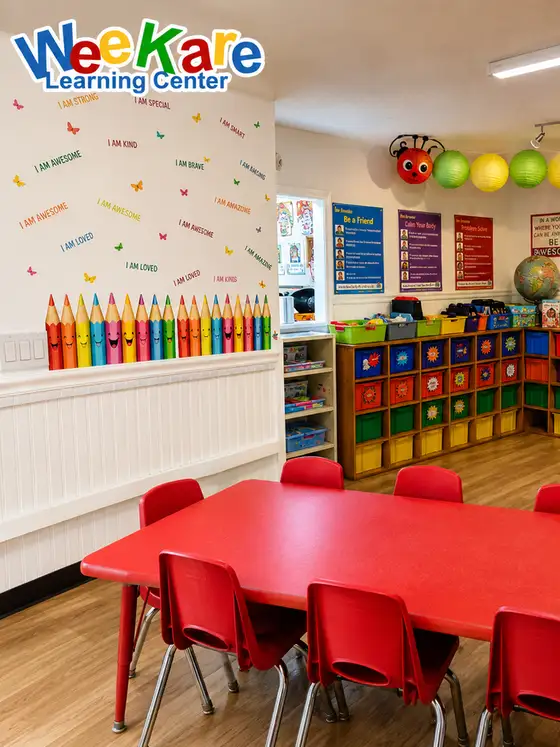 A classroom with a long red table, cubbies and a giant coloured-pencil mural