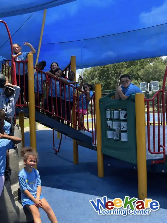 Children on the climbing frame beneath the blue shade sails